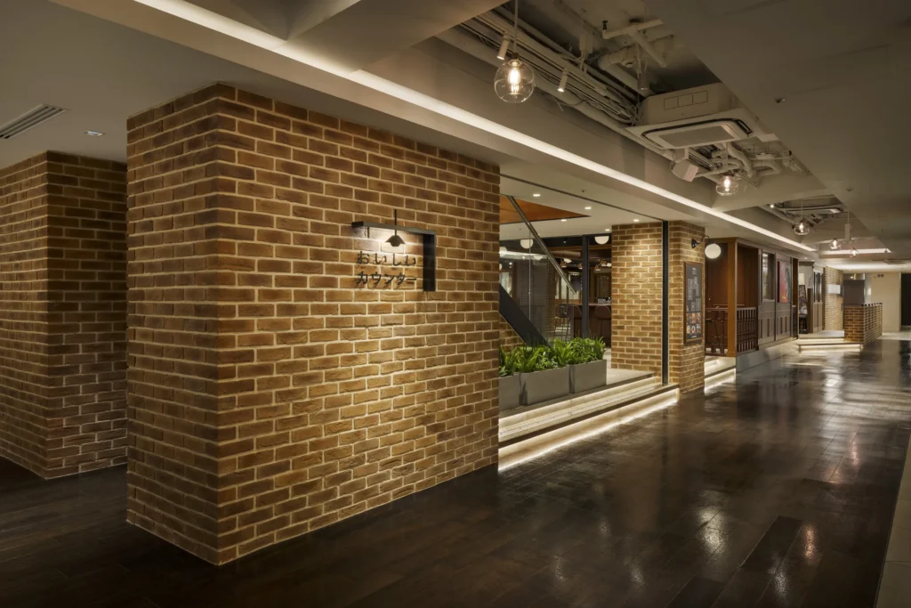 横浜MORE’S 9F おいしいカウンターにブリックタイルCAN’BRICK「セントジェームス（SJ-3）」をご採用いただきました。
 
 ブリックタイルがレストラン全体の内装に効果的に使用され、空間に温もりと高級感をもたらしています。レンガの自然な質感が、天井の露出した配線や木材の家具と調和し、モダンでありながらもクラシックな雰囲気を演出しています。
 
 植物が配置されたスペースや、オープンバーの柱など、レンガタイルが空間のアクセントとして機能し、各エリアをさりげなく区切りながらも統一感を保っています。落ち着いた照明とレンガの風合いが相まって、訪れるお客様にリラックスした雰囲気を提供し、居心地の良いダイニング体験を演出しています。
 
 英国で最もポピュラーなレンガを再現したブリックタイル、CAN’BRICK キャン'ブリック「St.James – セントジェームス(SJ)」。 古き良き時代の意匠を継承しながらも、馴染み易い色味と風合いは万人にレンガの暖かみを伝えます。